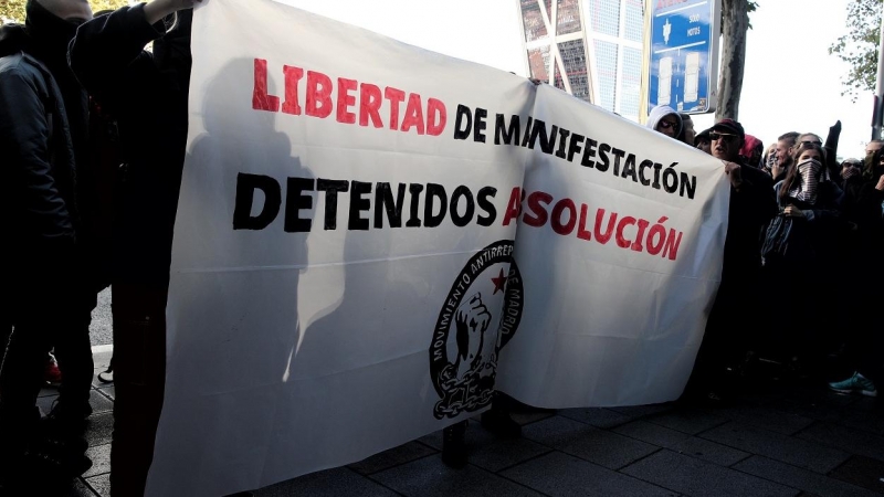 Jóvenes integrantes del Movimiento Antirrepresivo de Madrid con una pancarta en la que se lee, `Libertad de Manifestación, Detenidos Absolución´, concentrados frente a los juzgados de Plaza de Castilla en apoyo a los detenidos en el centro de Madrid duran