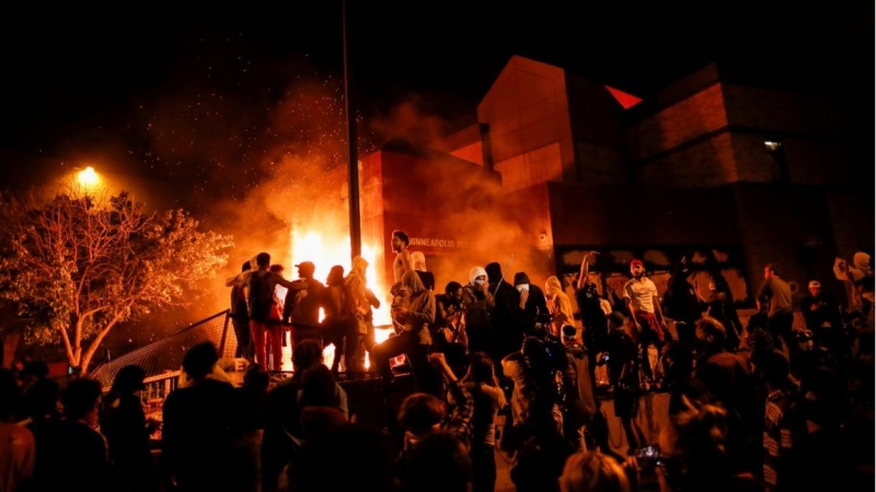 Los manifestantes se reúnen tras prender fuego a la entrada de una estación de policía mientras continúan las manifestaciones por George Floyd. REUTERS / Carlos Barria