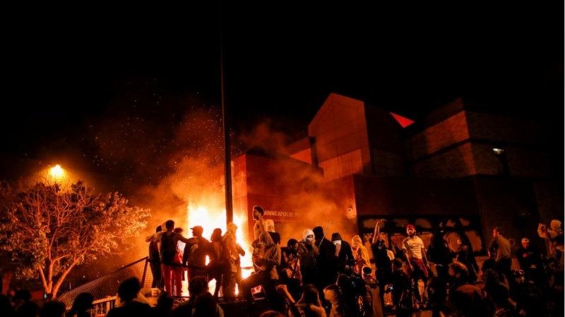 Los manifestantes se reúnen tras prender fuego a la entrada de una estación de policía mientras continúan las manifestaciones por George Floyd. REUTERS / Carlos Barria