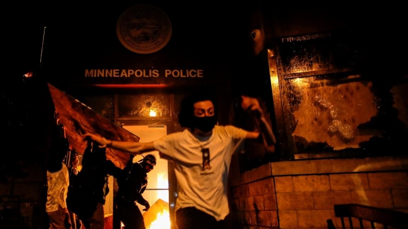 Los manifestantes corriendo tras prender fuego a la entrada de una estación de policía en Minneapolis. REUTERS / Carlos Barria