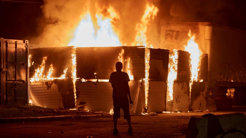 Los manifestantes se reúnen para ver un edificio de apartamentos en llamas cerca del tercer recinto de la Policía de Minneapolis. REUTERS / Adam Bettcher