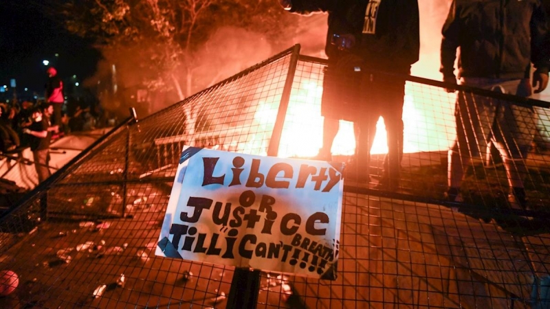 Los manifestantes aplauden mientras el fuego arde fuera del recinto policial de Minneapolis durante las protestas por la muerte de George Floyd. EFE / CRAIG LASSIG