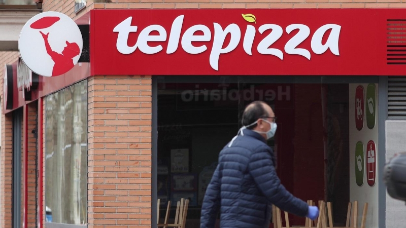 Un hombre protegido con mascarilla pasea cerca de un local de Telepizza, en Madrid. E.P./Eduardo Parra