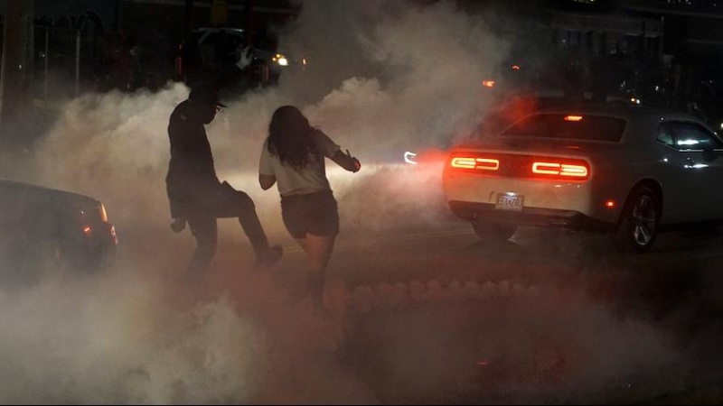 Un hombre patea un bote de gas lacrimógeno lejos de una mujer durante una protesta contra la muerte en la custodia policial de Minneapolis del hombre afroamericano George Floyd, en Ferguson, Missouri, Estados Unidos, 31 de mayo de 2020. REUTERS / Lawrence