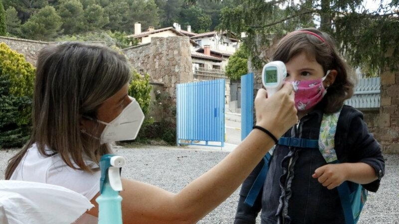 Una professora prenent la temperatura a una de les alumnes, a l'escola Els Ventets de Collsuspina, aquest dilluns. ACN