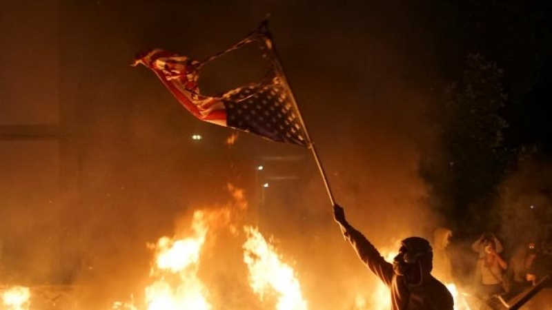 Un manifestante sostiene una bandera estadounidense quemada durante una protesta por George Floyd, en St. Louis, Missouri. REUTERS / Lawrence Bryant