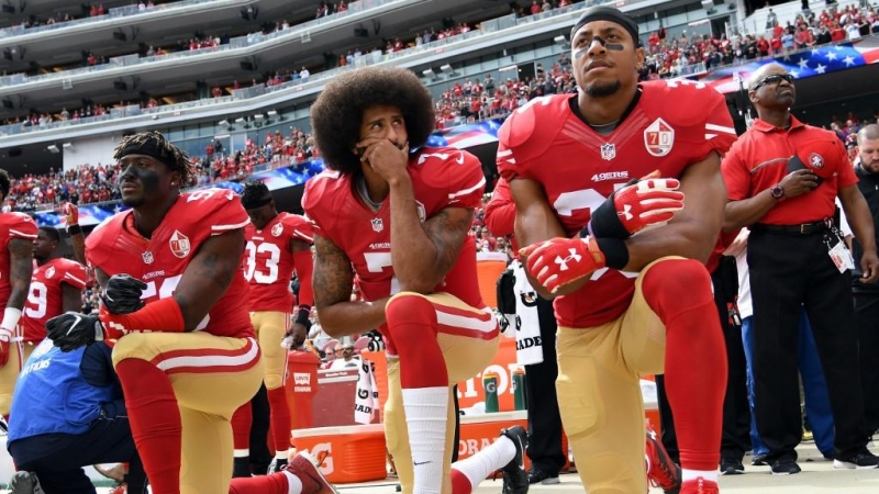 02/10/2016- Los jugadores Eli Harold, Colin Kaepernick y Eric Reid se arrodillan mientras suena el himno de EEUU durante un partido en señal de protesta en 2016. / GETTY IMAGES A TRAVÉS DE AFP