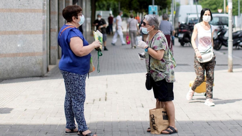 Dos mujeres mantienen la distancia social mientras hablan en una calle de Barcelona. - EFE