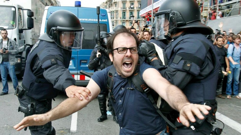 Dos policías intentan sujetar a una de las personas concentradas en la plaza Cataluña de Barcelona. ANDREU DALMAU (EFE)