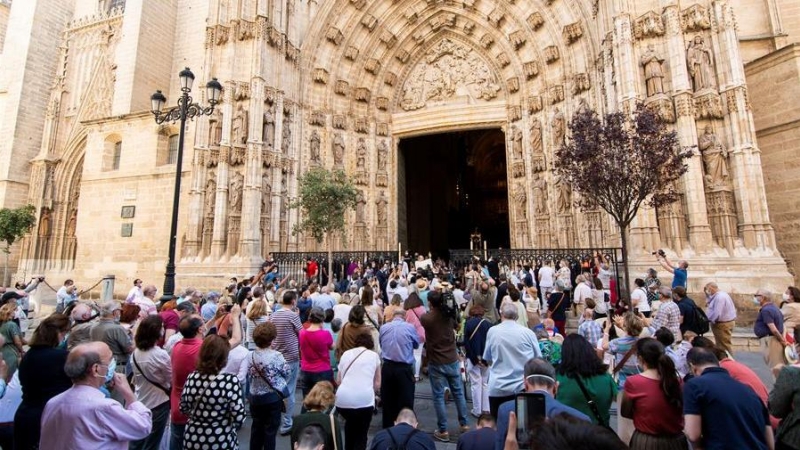 El arzobispo de Sevilla, Juan José Asenjo (c) muestra la Custodia de mano con el Cuerpo de Cristo en una de las puertas de la Catedral de Sevilla al suspenderse la procesión por las calles debido al estado de alarma por la crisis sanitaria de la covid-19