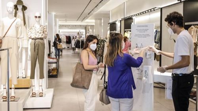 Dos clientas se desinfectan las manos con gel hidroalcohólico a la entrada de una tienda de ropa en Valencia.| Rober Solsona.  Europa Press