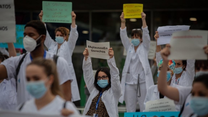 Decenas de miembros del personal sanitario protegidos con mascarilla sostienen carteles durante la concentración de sanitarios en el Día Internacional de la Enfermería a las puertas del Hospital Vall d'Hebron, en Barcelona. Europa Press / Archivo