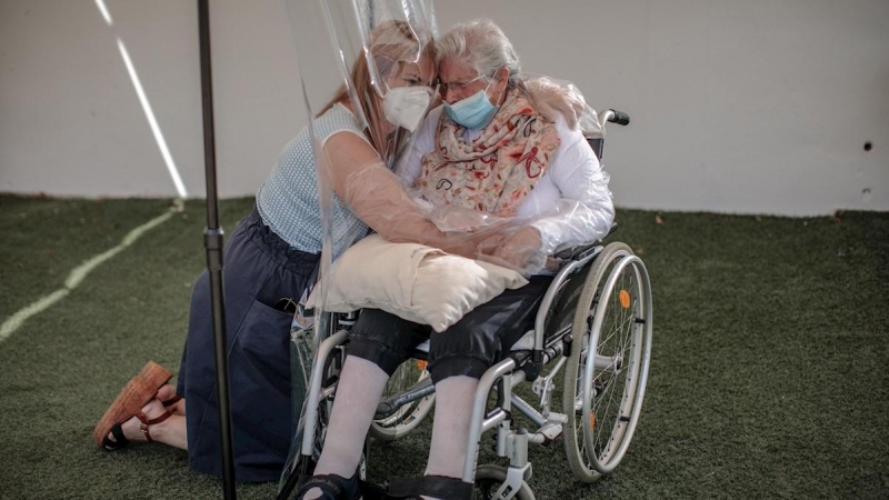 Una interna en una residencia de mayores en València abraza a su hija a través de un plástico habilitado para que los familiares se puedan dar su primer abrazo desde hace tres meses. - EFE/Biel Aliño