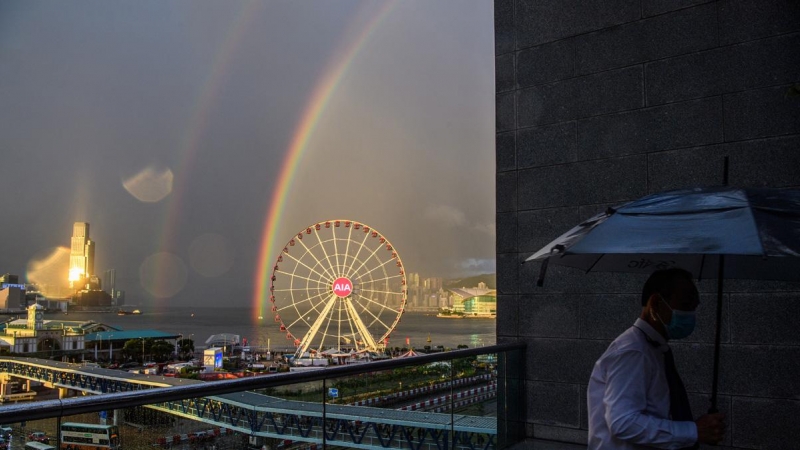 Un hombre usa su paraguas después de mirar dos arcoíris que aparecieron durante el atardecer después de una lluvia en Hong Kong el 16 de junio de 2020. Anthony WALLACE / AFP