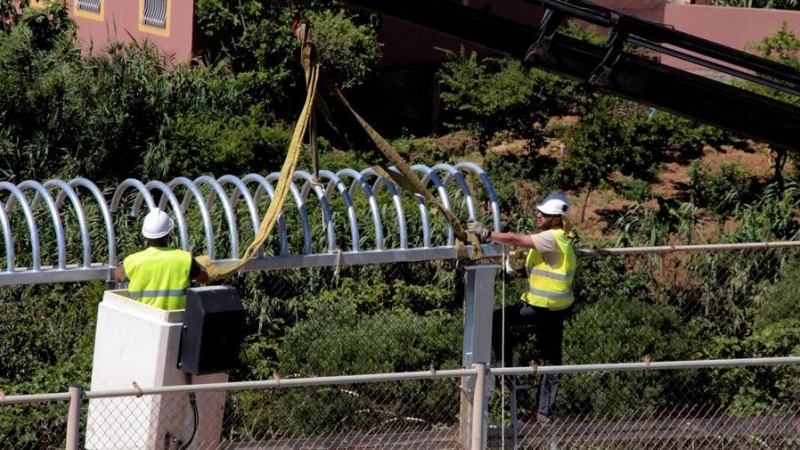 El personal encargado de las obras de reforma del perímetro fronterizo que separa Ceuta de Marruecos instala los primeros tubo antitrepados que sustituyen a las concertinas que coronaban el vallado fronterizo. EFE/ Reduan Dris