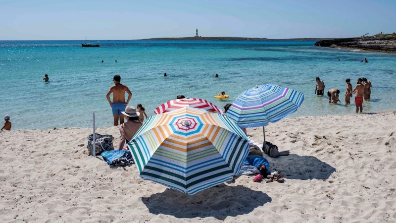 Varias personas disfrutan del buen tiempo durante el primer día de verano y primer día de la nueva normalidad en la playa de Punta Prima, Menorca. EFE/ David Arquimbau Sintes