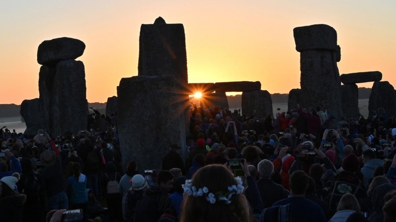 Los juerguistas miran el amanecer en Stonehenge, cerca de Amesbury, en Wiltshire, en el sur de Inglaterra, el 21 de junio de 2019, mientras celebran el solsticio de verano. El festival, que data de miles de años, celebra el día más largo del año cuando el