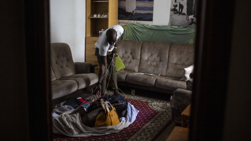 Samba, senegalés de 28 años, muestra el el salón de su casa de Lavapiés la manta con los bolsos que no ha podido vender en la calle durante el confinamiento decretado por el coronavirus.-  JAIRO VARGAS