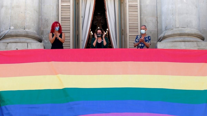 La alcaldesa de Barcelona, Ada Colau (c), preside la colgada del pendón del arcoíris con motivo del Día del Orgullo y Liberación LGTBI, este domingo enelbalcón del Ayuntamiento de la ciudad. EFE/Quique Garcia