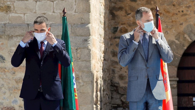 01/07/2020.- El presidente del Gobierno, Pedro Sánchez (i) y el rey Felipe VI (d) se ponen las mascarillas antes de la foto oficial en la explana del castillo de Elvas durante el acto oficial de la reapertura, tras tres meses y medio cerradas por el coro