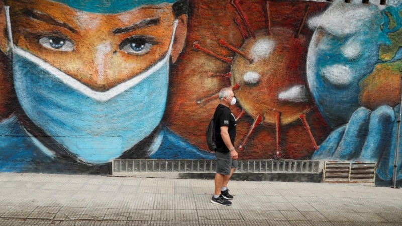 01/07/2020.- Un hombre camina junto a un mural en homenaje a los sanitarios que han estado en primera línea en la batalla contra el coronavirus en una calle de Melide en A Coruña. EFE/ Eliseo Trigo