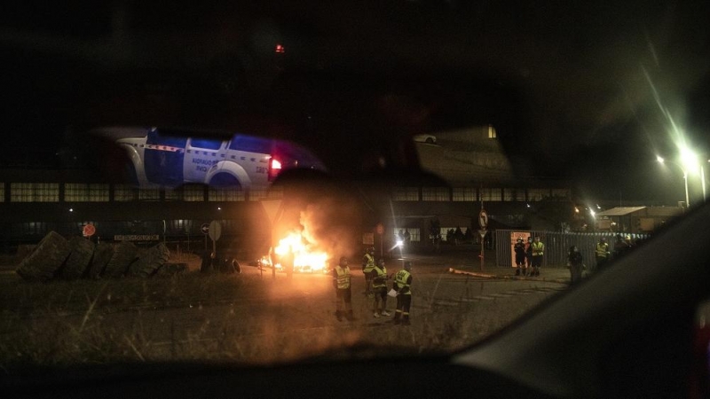 Trabajadores controlan el acceso de los empleados en servicios mínimos durante el cambio de turno a la entrada de la factoría de Alcoa, custodiada por la Guardia Civil. MANU BRABO