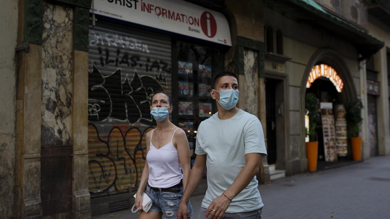 Una parella passa per davant d'una oficina de turisme tancada, a Barcelona. LAIA ROS
