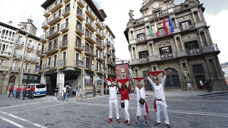 06/07/2020.- Un grupo de personas posan para una fotografía con sus pañuelos alzados en la Plaza del Ayuntamiento este lunes, 6 de julio, cuando debería lanzarse el tradicional chupinazo que diera inicio a las fiestas de San Fermin 2020 suspendidas por l