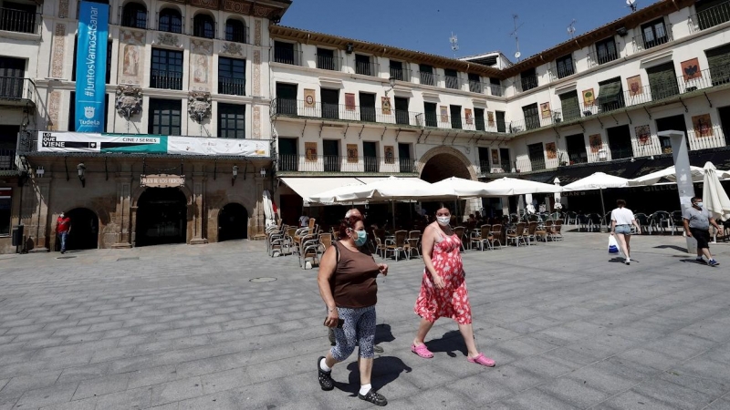 Varias personas pasean con su mascarilla puesta por la Plaza de los Fueros de Tudela donde se ha detectado un brote de coronavirus tras la celebración de una boda. EFE/ Jesus Diges