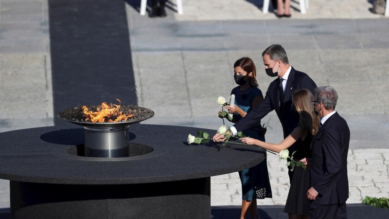 El rey Felipe VI, la Princesa de Asturias, la jefa del servicio de Urgencias del Hospital Vall d'Hebron, Aroa López (i), y Hernando Calleja (d), hermano del periodista José María Calleja, fallecido durante la pandemia, realizan la ofrenda floral en el peb