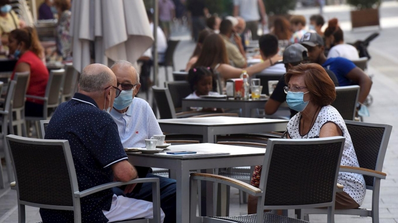 Varias personas con mascarilla disfrutan en un bar. EFE/ Javier Blasco /Archivo