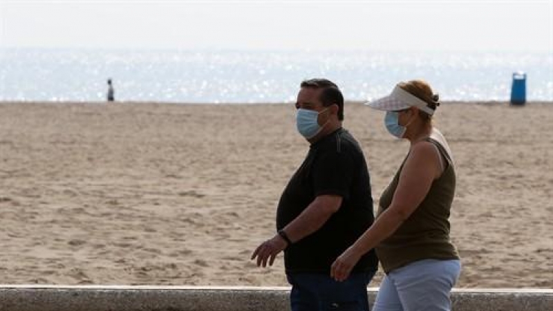 Dos personas protegidas con mascarilla pasean por la playa en València. /Europa Press