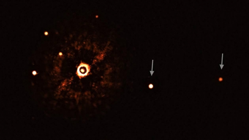 Estrella TYC 8998-760-1 (con su luz bloqueada) y sus dos exoplanetas (marcados con flechas). Los otros puntos brillantes son estrellas del fondo. / ESO/Bohn et al.