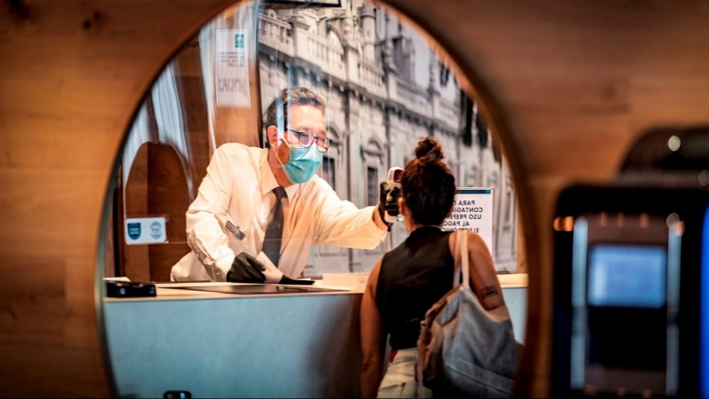 Un recepcionista de hotel toma la temperatura a una huesped por la pandemia de coronavirus. EFE/ José Manuel Vidal/Archivo