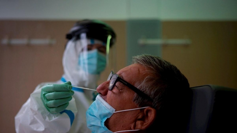 Una profesional sanitaria realiza una prueba PCR a un paciente. EFE/Enric Fontcuberta/Archivo