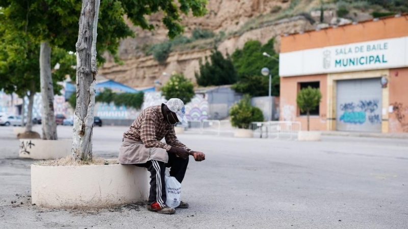 Un temporero senegalés se sienta frente a un gimnasio que alberga trabajadores estacionales de la recogida de la fruta en la localidad oscense de Fraga (Huesca).- Pau BARRENA / AFP