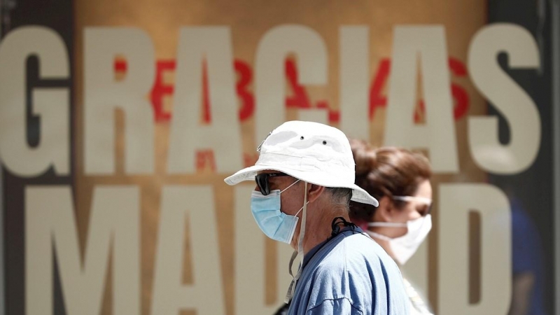 Viandantes caminan por Madrid protegidos con mascarilla, este martes. | EFE