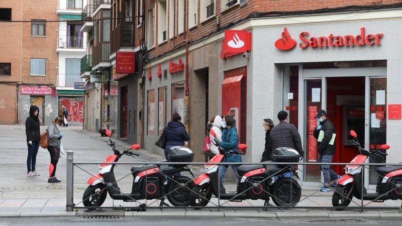 Varias personas esperan para entrar a una oficina del Banco Santander durante el estado de alarma, en Madrid. E.P./Marta Fernández