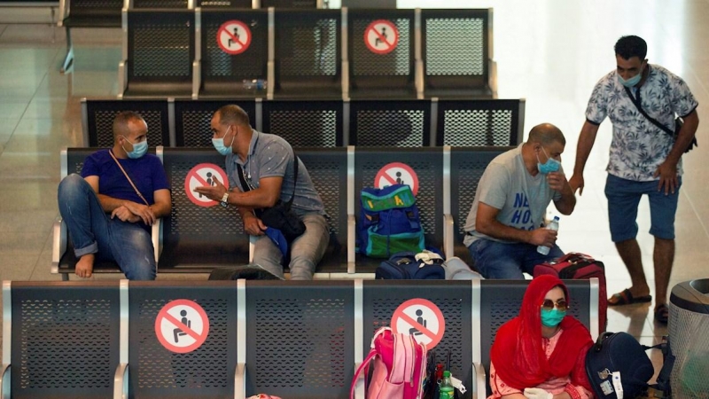 Viajeros con máscaras sanitarias descansan este miércoles en la Terminal 1 del aeropuerto Josep Tarradelles | EFE
