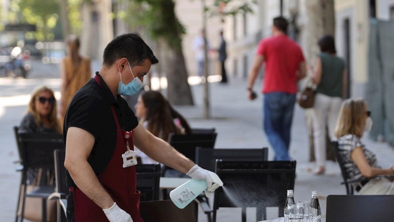 Un camarero desinfecta una mesa tras las marcha de los clientes la terraza de un bar del centro de Madrid, este miércoles. | EFE