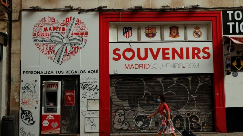 Una mujer con mascarilla pasa por delante de una tienda de souvenirs cerrada en el centro de Madrid. REUTERS/Susana Vera