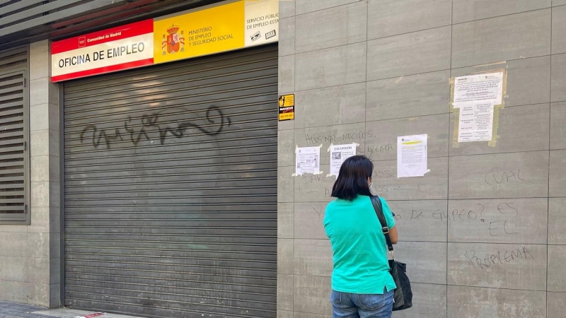 Una persona observa uno de los carteles con instrucciones para hacer trámites por internet colocados en la fachada de una oficina del SEPE. E.P./Eduardo Parra