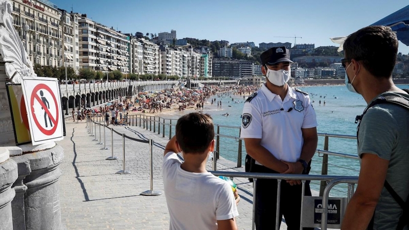 Un agente de la Policía Municipal impide el acceso este miércoles a la playa de La Concha de San Sebastián, coincidiendo con la pleamar, para evitar un exceso de aforo. EFE/Javier Etxezarreta