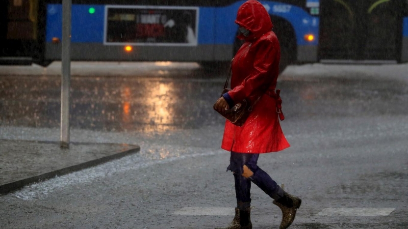 Una mujer camina por la calle durante la tormenta registrada esta mañana en Madrid. EFE/ Fernando Alvarado