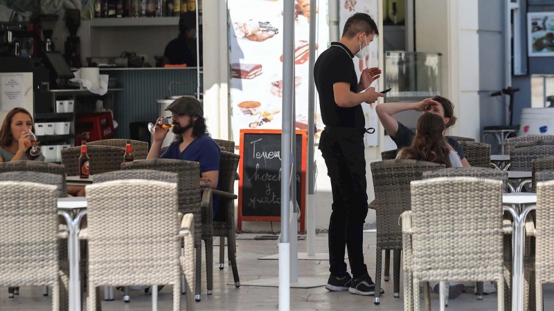 un camarero atiende a unos clientes en la terraza de un bar. EFE/Ana Escobar