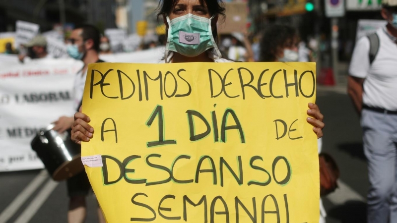 Una mujer sujeta una pancarta en la que se lee 'Pedimos derecho a 1 día de descanso semanal' durante una manifestación de los médicos internos residentes (MIR) en Madrid. /Europa Press