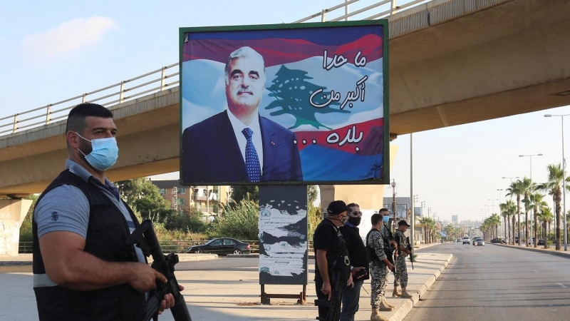 Miembros de las fuerzas de seguridad montan guardia en Sidón, al sur del Líbano, cerca de un cartel con la imagen del exprimer ministro libanés, Rafik al-Hariri, quien murió en un atentado suicida en 2005. REUTERS / Aziz Taher