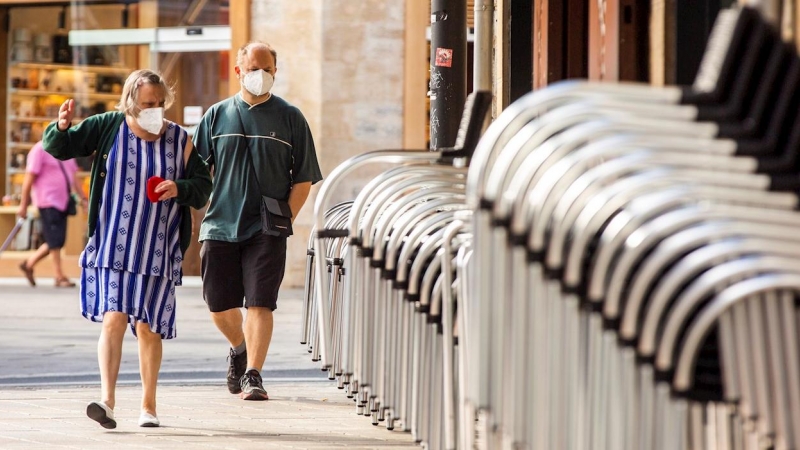 Un hombre y una mujer pasan ante la terraza recogida de un bar en el centro de Vitoria este miércoles, en el que se ha sabido que tres personas fallecieron la semana pasada en Euskadi con infección por coronavirus. EFE/ David Aguilar