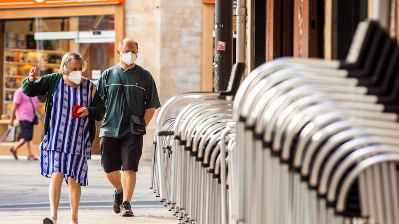 Un hombre y una mujer pasan ante la terraza recogida de un bar en el centro de Vitoria este miércoles, en el que se ha sabido que tres personas fallecieron la semana pasada en Euskadi con infección por coronavirus. EFE/ David Aguilar