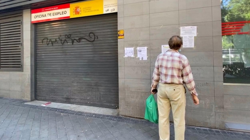 Una persona observa uno de los carteles con instrucciones para hacer trámites por internet colocados en la fachada de una oficina de empleo en Madrid. E.P./Eduardo Parra